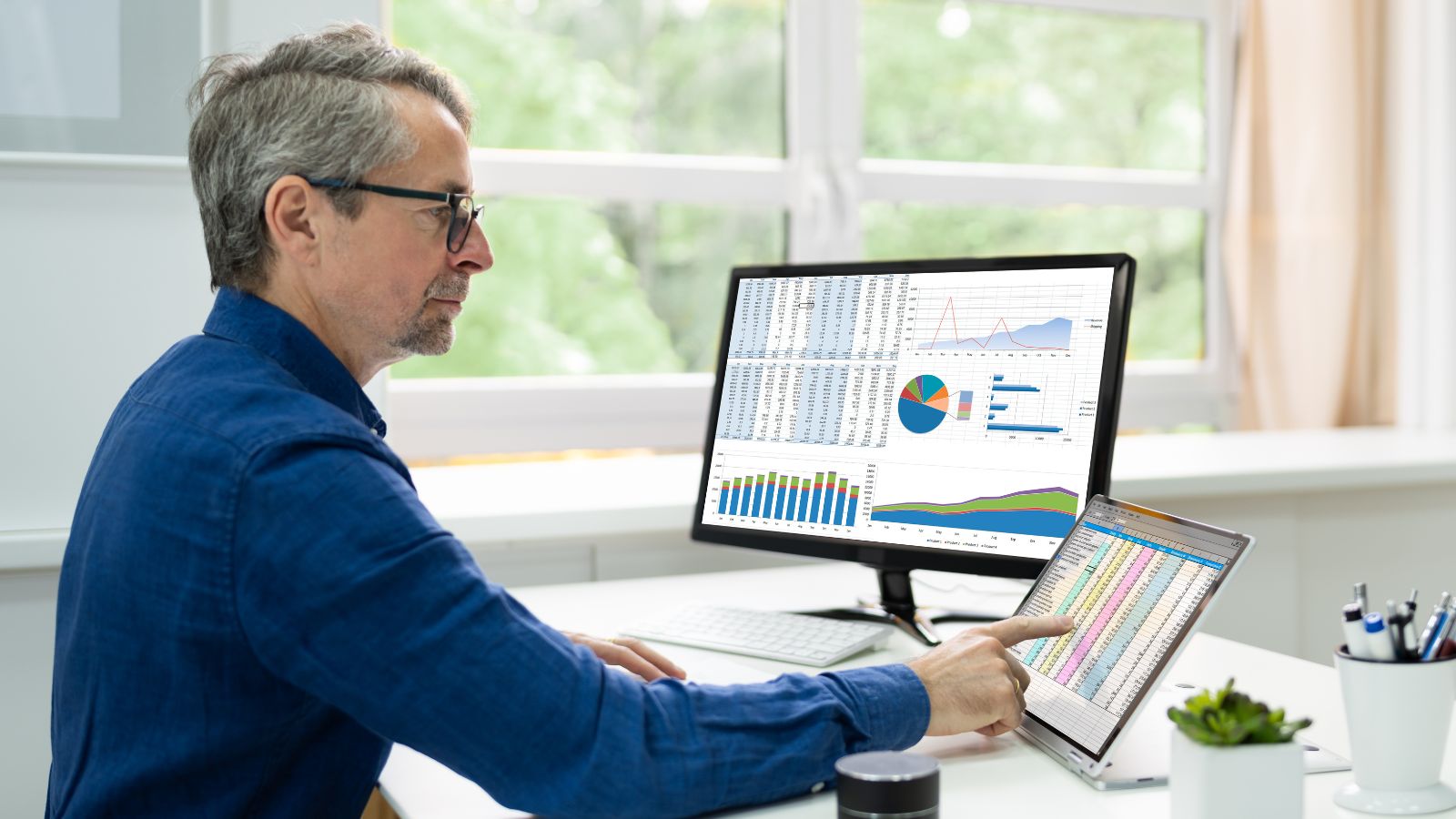 man looking at computer screen with spreadsheets