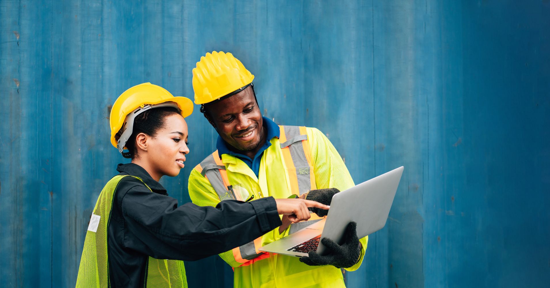 two construction workers looking at a laptop